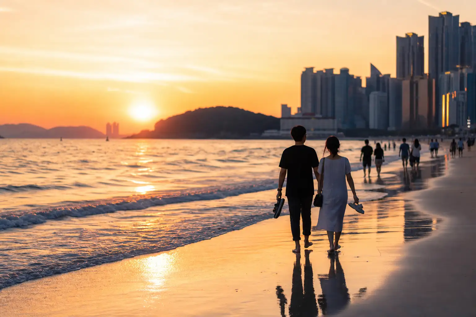 해운대 해수욕장의 여름 저녁 풍경, 노을과 백사장을 걷는 사람들